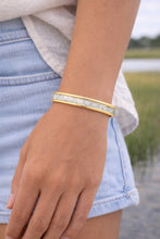Gold bracelet on a wrist with a natural background
