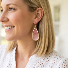 Woman wearing a red and white striped earring with a blurred background