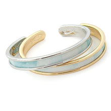 Three bracelets in gold, silver, and light blue on a white background