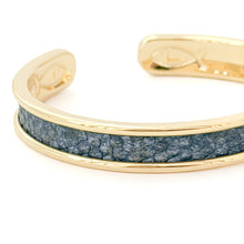 Gold bracelet with a blue stone inlay on a white background