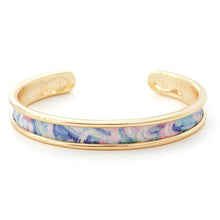 Gold bangle with a colorful fabric interior on a white background