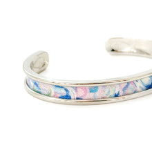 Silver bracelet with a colorful fabric band on a white background