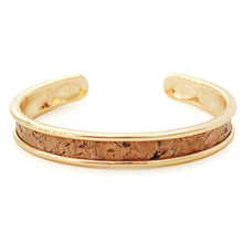 Gold bracelet with cork interior on a white background