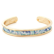Gold bracelet with a blue floral pattern on a white background