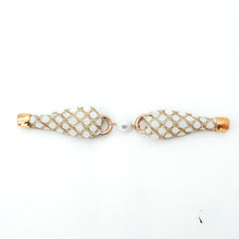 Pair of earrings with gold and white mesh design on a white background