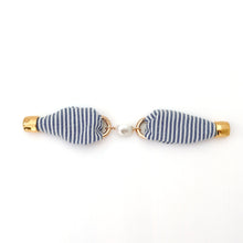Pair of earrings with blue and white striped design on a white background