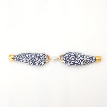 Pair of earrings with blue and white patterned design on a white background