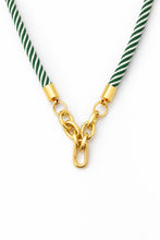 Necklace with green and white striped cord and gold clasp on a white background