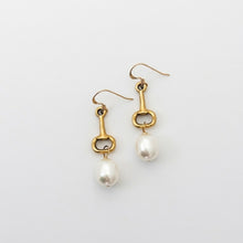 Gold earrings with pearl drops on a light gray background