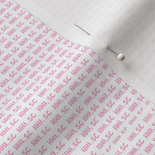 Fabric with pink text pattern and pins on a light background
