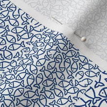Fabric with blue fish pattern pinned to a white background