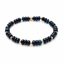 A beaded stretch bracelet featuring dark blue and black stone beads separated by small gold metallic spacer beads, shown on a clean white background.