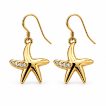 A pair of gold starfish drop earrings with small clear stones along one arm of each starfish, shown on a plain white background.