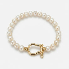Pearl bracelet with a gold clasp on a light gray background