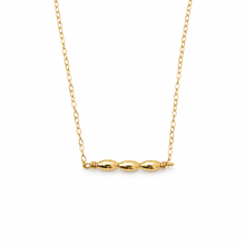 A delicate gold chain necklace featuring a horizontal bar with three polished oval beads, displayed against a solid white background.