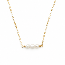 A delicate gold chain necklace featuring three small, lustrous white freshwater pearls strung horizontally on a gold wire bar at the center, set against a plain white background.