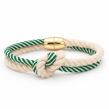 Nautical-style bracelet with green and white striped cord and gold clasp on a white background