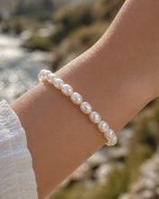 Pearl bracelet on a wrist with a blurred natural background