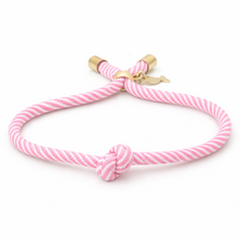 Pink striped bracelet with a gold clasp on a white background