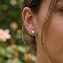 Close-up of a person wearing a silver earring with a blurred natural background