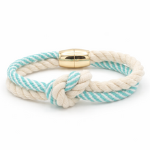 Nautical-style bracelet with turquoise and white stripes and a gold clasp on a white background