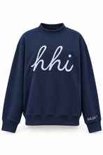 A navy blue crewneck sweatshirt featuring the word 'hhi' in white cursive script across the chest, with 'Little Hi' embroidered on the left sleeve cuff, shown against a plain white background.