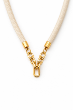 Gold chain necklace with beige cord on a white background