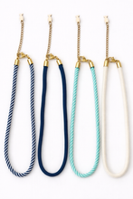 Four necklaces with different colored ropes and gold clasps on a white background