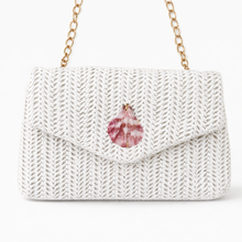 White knitted handbag with a pink gemstone on a white background