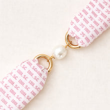 Fabric keychain with gold ring and pearl on a white background