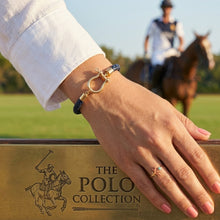 Hand wearing a gold bracelet with a ring, with 'The Polo Collection' logo in the foreground.