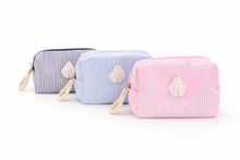 Three striped cosmetic bags with shell decorations on a white background