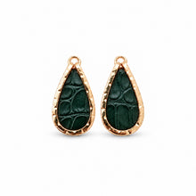 A pair of teardrop-shaped earrings with textured dark green leather inserts and hammered rose gold metal borders, shown on a clean white background.