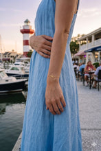 Person wearing a blue dress with a lighthouse and marina in the background