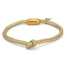 Gold bracelet with a knot design on a white background