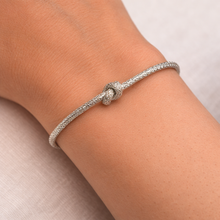 Silver bracelet on a wrist with a neutral background