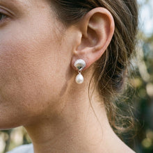 Model wearing a silver-tone scallop stud with a white pearl drop.