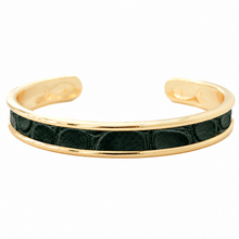 A gold-tone cuff bracelet featuring a central channel inlaid with textured dark green leather.