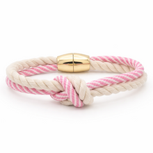 Pink and white braided bracelet with a gold clasp on a white background