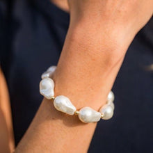 Pearl bracelet on a person's wrist against a dark background