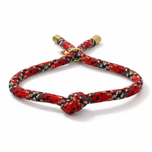 Red braided bracelet with a gold clasp on a white background
