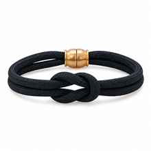 A black braided rope bracelet with a knotted center detail and a polished gold cylindrical clasp, shown on a clean white background.