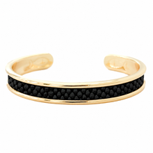 A gold-toned open cuff bracelet featuring a central channel set with small black round stones, shown against a plain white background.