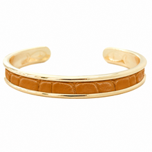 A gold-plated cuff bracelet featuring a central inlay of textured tan leather with a crocodile or alligator pattern, shown against a plain white background.