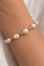 Pearl bracelet on a wrist with a neutral background