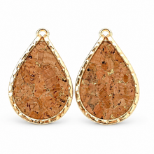 A pair of teardrop-shaped earrings with textured natural cork centers and hammered gold-tone edges, shown on a clean white background.