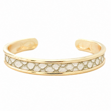 A gold-toned open cuff bracelet featuring a textured, honeycomb-like inlay of white stones across the front, set against a plain white background.