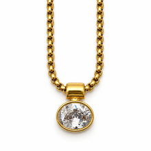 A gold chain necklace with a round bezel-set clear gemstone pendant, shown against a plain white background.