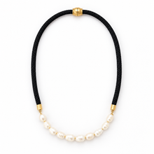 A black braided cord necklace with a curved section of white baroque pearls and gold-tone metal accents, shown on a plain white background.