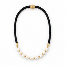 A black braided cord necklace with a curved section of white baroque pearls separated by small gold spacer beads, finished with gold end caps and a gold clasp, shown on a plain white background.